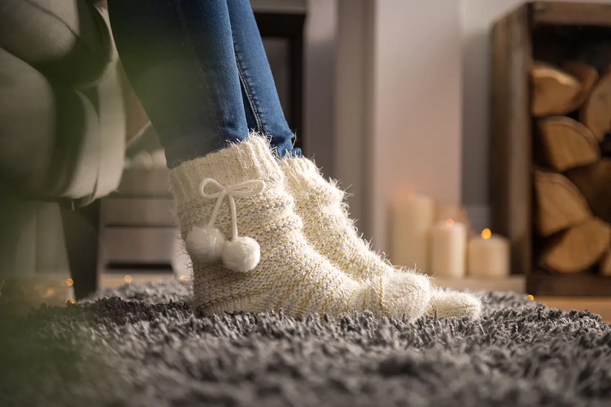 A close up image of some Totes slippers, in a cosy living room setting