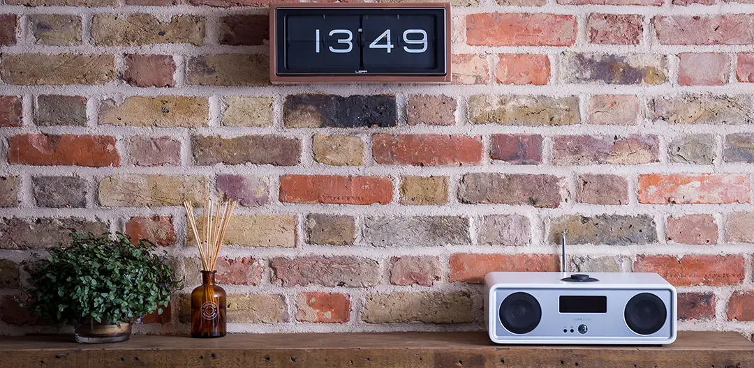 An image of the Ruark R4 integrated music system, sat on a wooden shelf, in front of a brick wall.