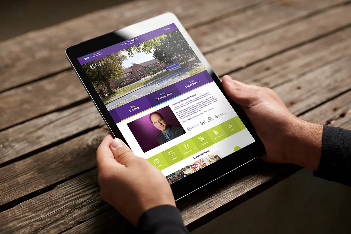 An image of a man holding an iPad with the new Thorpe Hall website on display