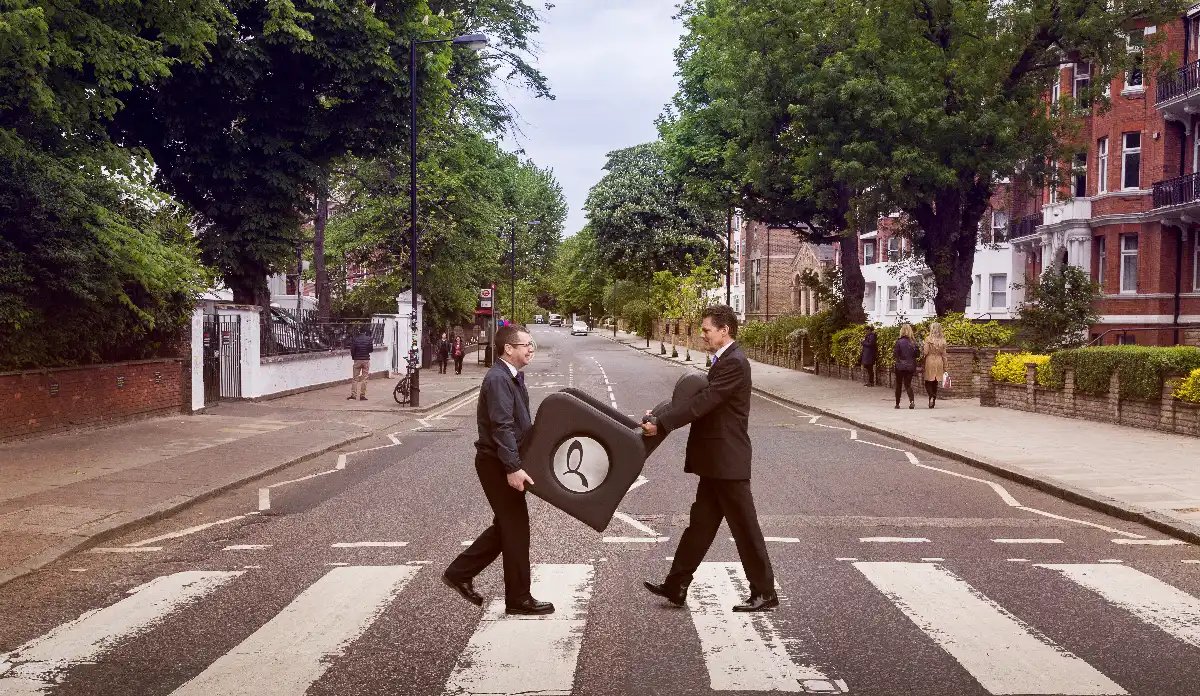 An image of two well dressed men crossing the 'Abbey Road' zebra crossing, while carrying a Euro Group cinema chair