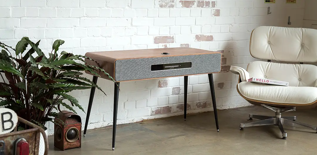 An image of the Ruark R7 high fidelity radiogram, sat in front of a white brick wall.